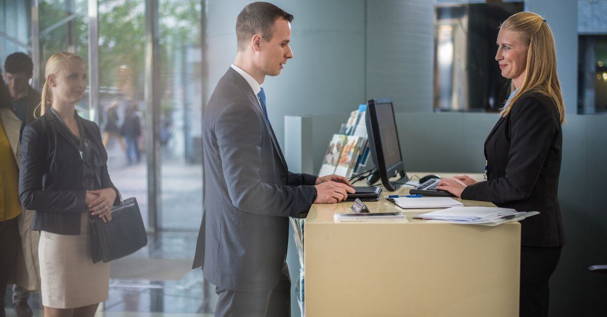 Bank teller speaking to man in line 