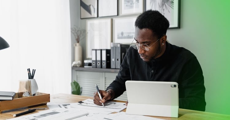 Man using tablet and writing notes with green glow 