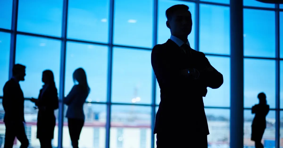 Silhouette of man with arms crossed and people standing people him