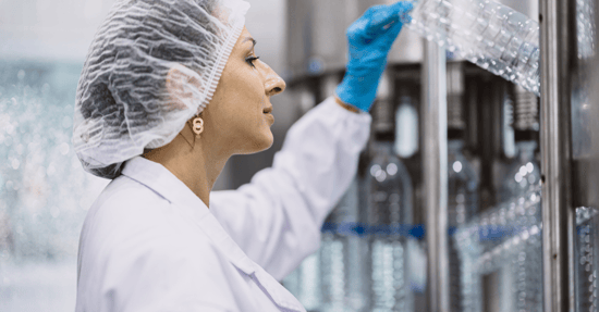 Woman with hair net wearing lab coat examining plastic 