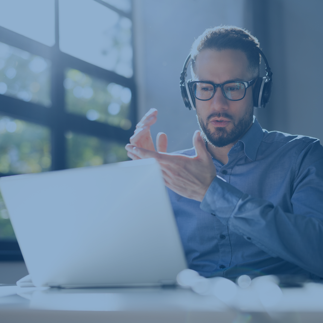 Man with headphones clapping hands while watching webinar on laptop