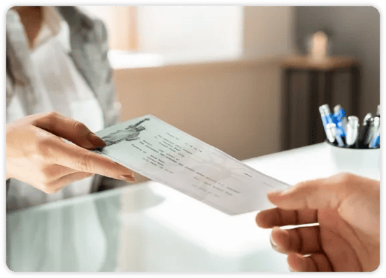 bank teller handing check to customer from across the counter