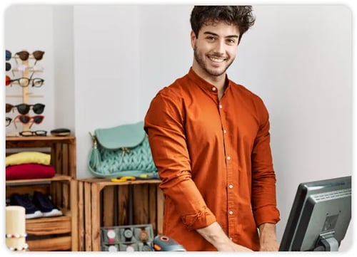 Retail employee in orange shirt working behind a counter