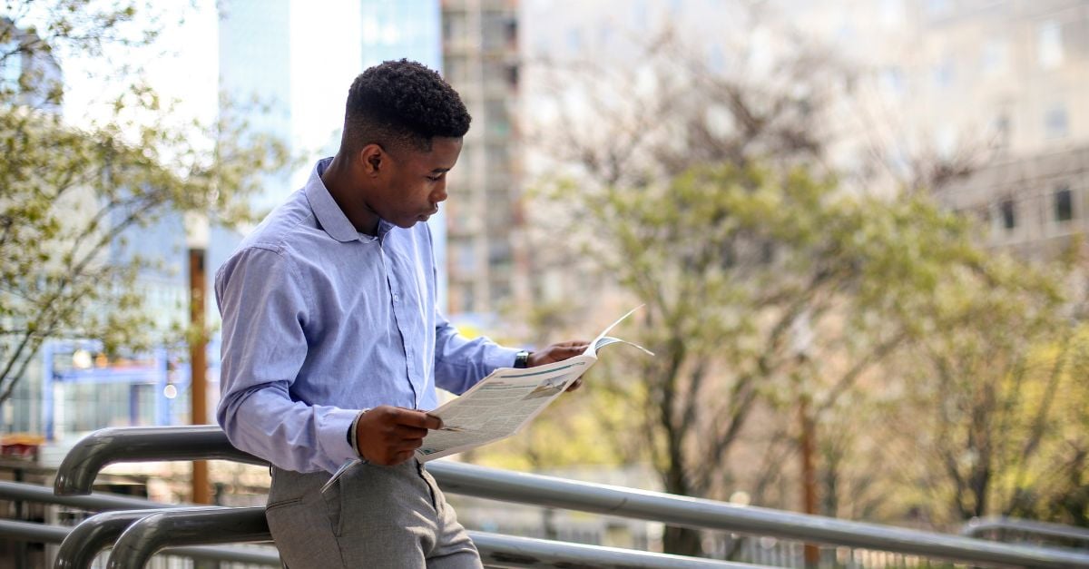 Man reading newspaper outside