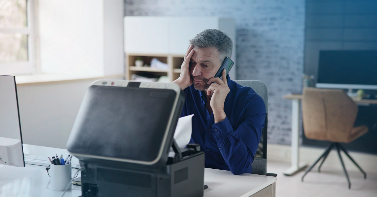 Confused man on the phone looking at printer