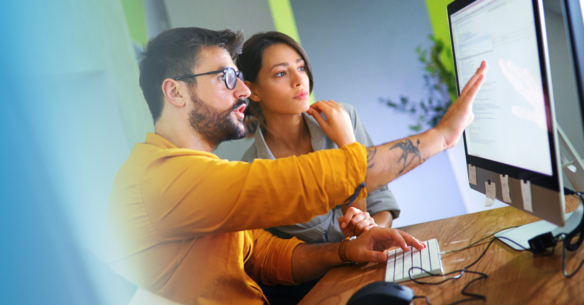 Man showing woman how to use software at desk