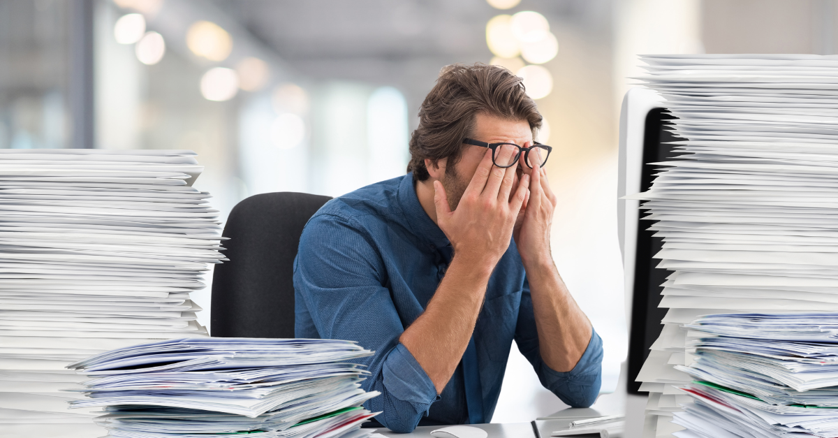 Frustrated main surrounded by stacks of paper and mail 