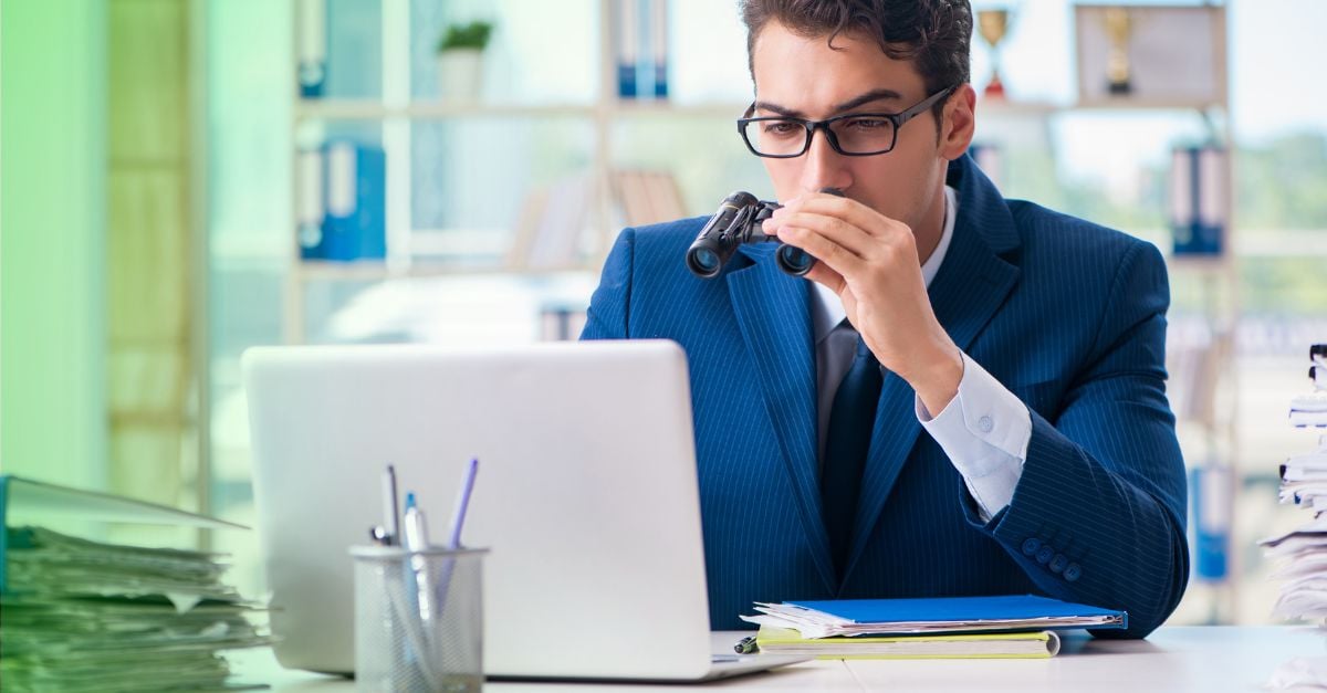 Accountant with binoculars examining fraud on laptop 